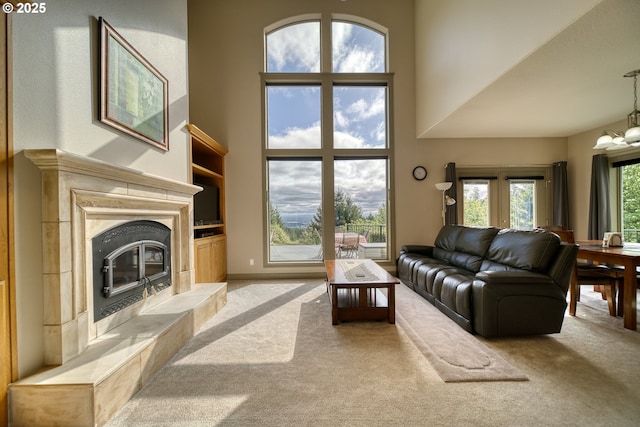 living area featuring a high ceiling, an inviting chandelier, light carpet, and a healthy amount of sunlight
