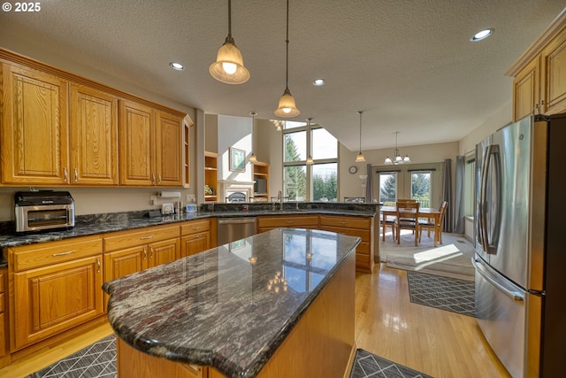 kitchen with open shelves, light wood-type flooring, a textured ceiling, a sink, and appliances with stainless steel finishes