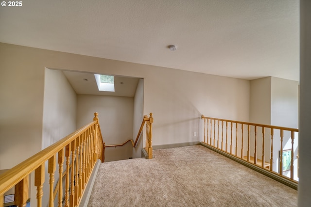 corridor with a skylight, carpet floors, and an upstairs landing