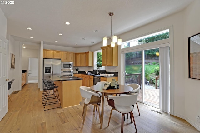 15017 SW Telluride Ter, Beaverton, OR 97007 - kitchen with stainless steel appliances, a center island, light wood-style floors, recessed lighting, and dark countertops