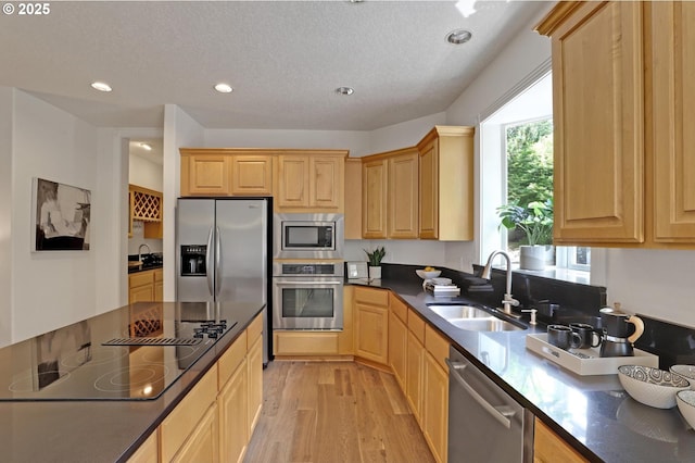 15017 SW Telluride Ter, Beaverton, OR 97007 - kitchen featuring appliances with stainless steel finishes, light brown cabinets, dark countertops, light wood finished floors, and recessed lighting