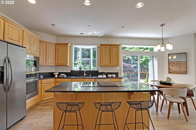 15017 SW Telluride Ter, Beaverton, OR 97007 - kitchen with stainless steel appliances, healthy amount of natural light, a breakfast bar area, dark countertops, and a textured ceiling