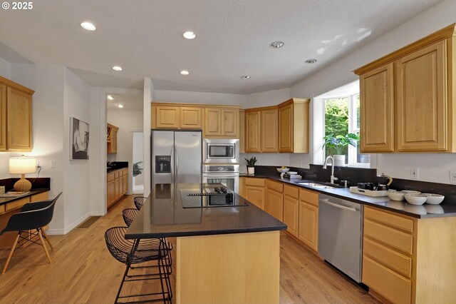 15017 SW Telluride Ter, Beaverton, OR 97007 - kitchen featuring stainless steel appliances, dark countertops, a breakfast bar area, light wood-style floors, and recessed lighting
