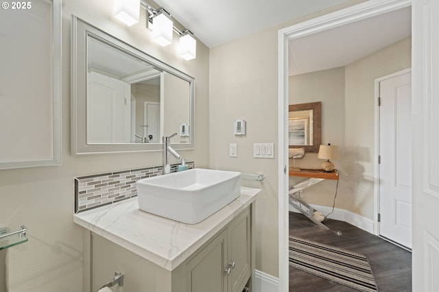 bathroom featuring baseboards, vanity, decorative backsplash, and wood finished floors