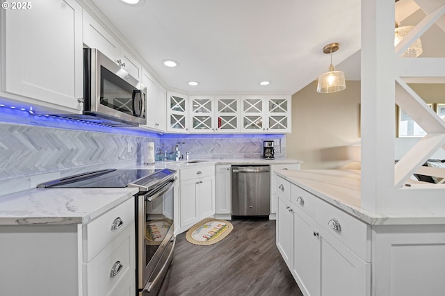 kitchen featuring light stone counters, stainless steel appliances, white cabinetry, decorative backsplash, and dark wood-style floors