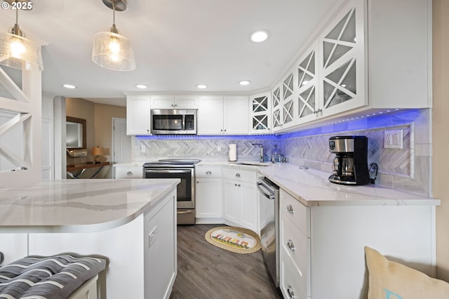 kitchen featuring tasteful backsplash, dark wood finished floors, glass insert cabinets, stainless steel appliances, and a sink