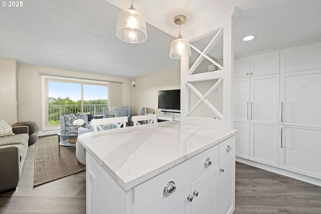 kitchen with light stone counters, white cabinets, open floor plan, a center island, and dark wood-style floors