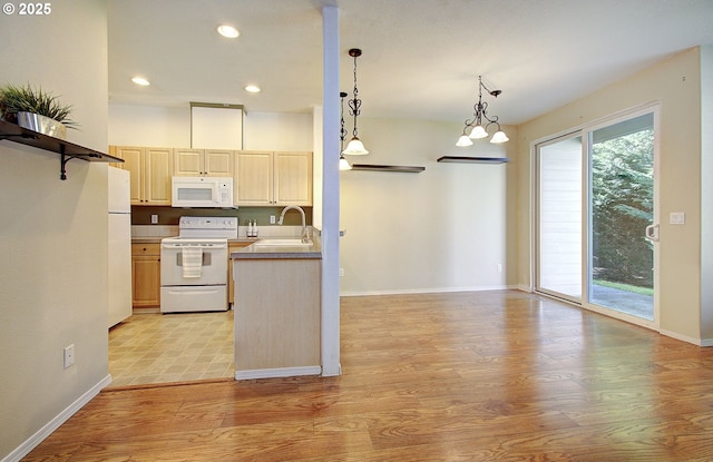 kitchen with pendant lighting, light countertops, light wood-style floors, a sink, and white appliances