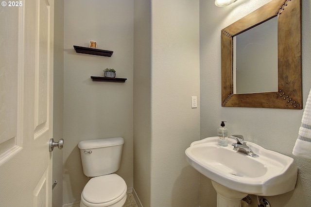 bathroom featuring toilet, baseboards, and a sink