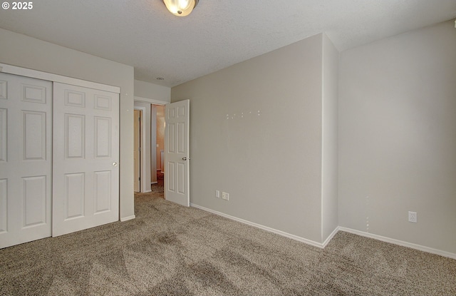 unfurnished bedroom with carpet floors, a closet, a textured ceiling, and baseboards