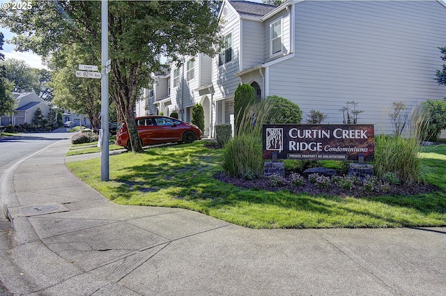 community / neighborhood sign featuring a yard and a residential view