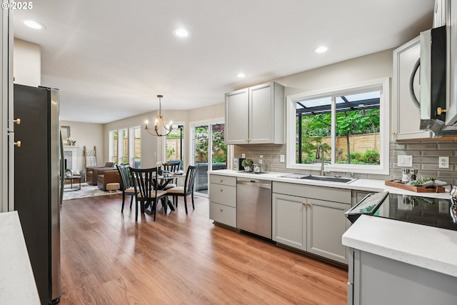 7330 SW Kelsi Ct, Portland, OR 97223 - kitchen featuring stainless steel appliances, a sink, backsplash, light wood-style floors, and recessed lighting