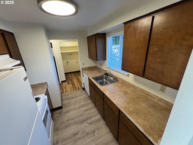 kitchen featuring light wood-type flooring, white appliances, a sink, and dark brown cabinets