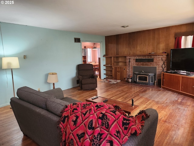 28213 Hunter Creek Hts, Gold Beach, OR 97444 - living room featuring wood walls, a wood stove, wood finished floors, and visible vents