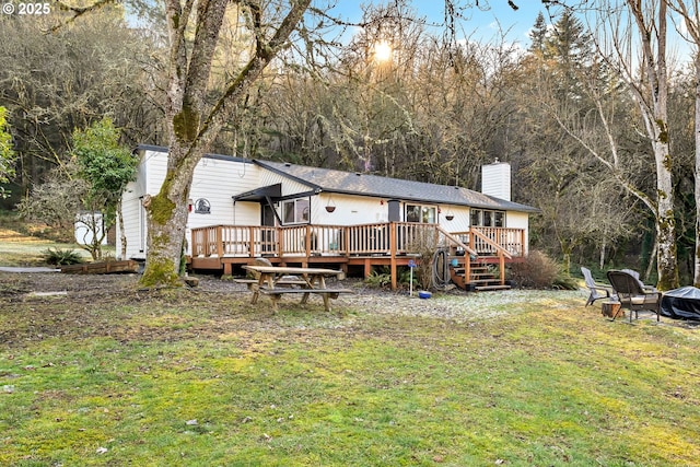 back of house featuring a yard, an outdoor fire pit, and a deck