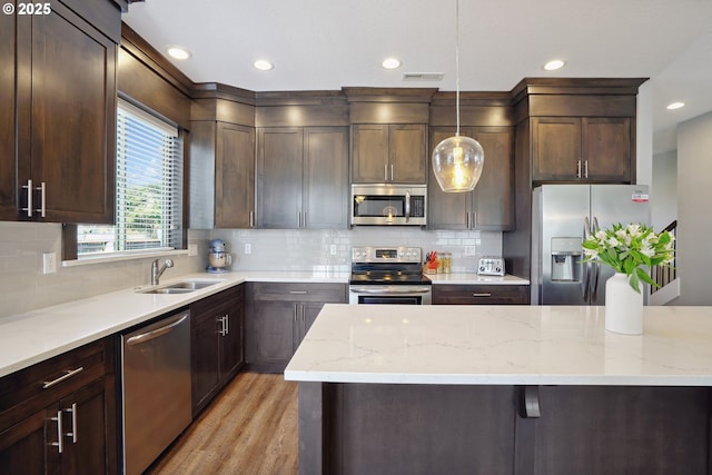 1522 NE Sunrise Ln, Hillsboro, OR 97124 - kitchen with dark brown cabinetry, light stone counters, a sink, light wood finished floors, and stainless steel appliances