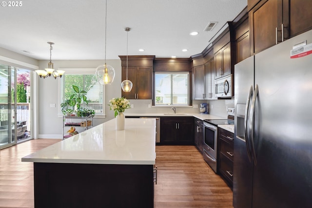 1522 NE Sunrise Ln, Hillsboro, OR 97124 - kitchen with visible vents, a sink, light countertops, light wood finished floors, and stainless steel appliances