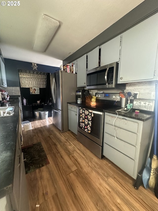 585 Robinhood Ave, Lakeside, OR 97449 - kitchen with stainless steel appliances, wood finished floors, dark countertops, and white cabinets