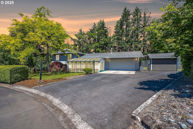 view of front of home featuring an outbuilding, driveway, an attached garage, and fence