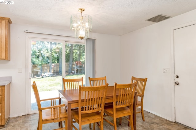 dining area with a textured ceiling, a chandelier, visible vents, and baseboards