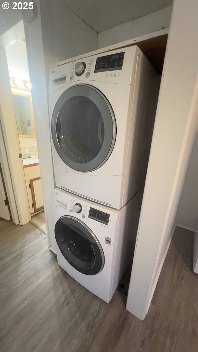 laundry room with laundry area, stacked washer / dryer, and wood finished floors