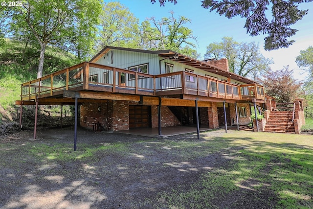 back of property with a chimney, stairway, a deck, and driveway