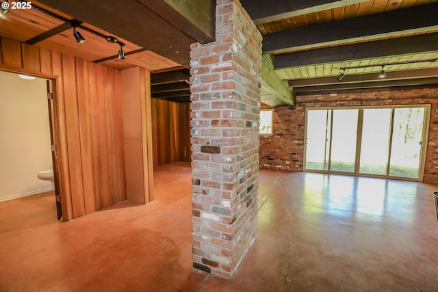 below grade area featuring track lighting, brick wall, wood ceiling, and wooden walls