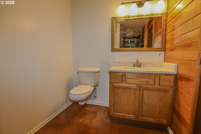bathroom with baseboards, concrete floors, vanity, and toilet