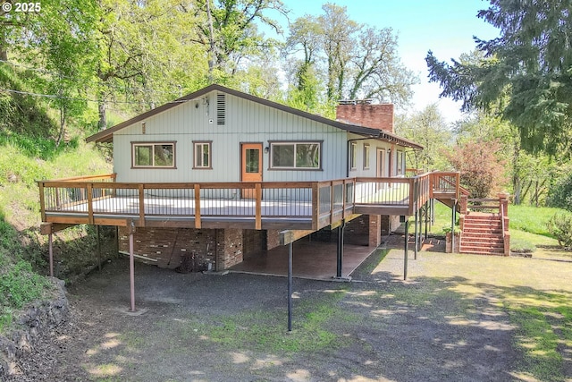 rear view of house featuring stairway, a wooden deck, and a chimney