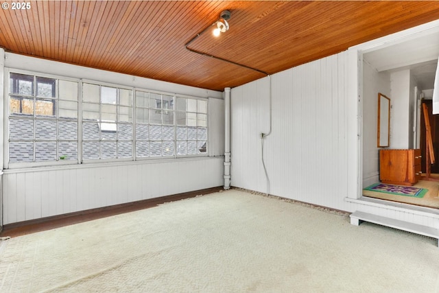 carpeted empty room featuring a healthy amount of sunlight and wooden ceiling