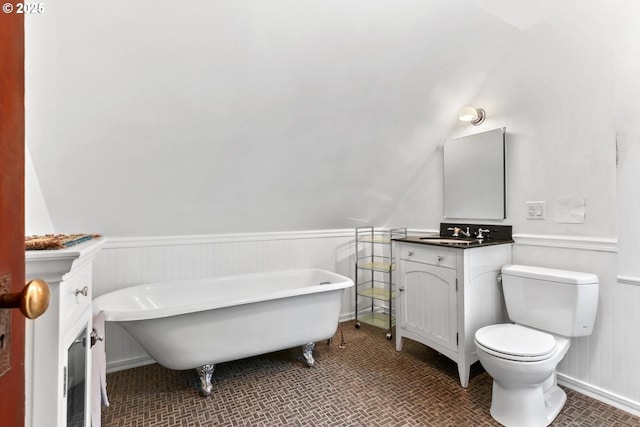 bathroom with vanity, a bath, lofted ceiling, and toilet