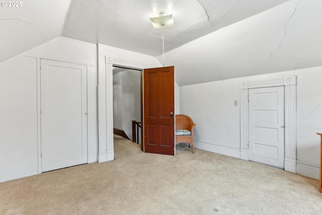 bonus room with vaulted ceiling and light carpet