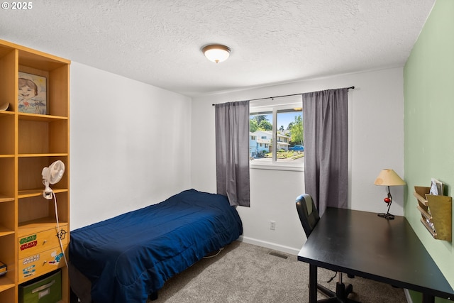 carpeted bedroom with a textured ceiling, a desk, and baseboards