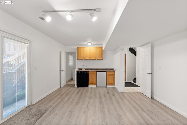 kitchen with light wood-style floors, baseboards, refrigerator, and track lighting