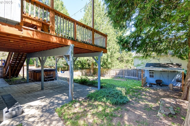 fenced backyard with a hot tub, a patio, a wooden deck, an outdoor structure, and a shed