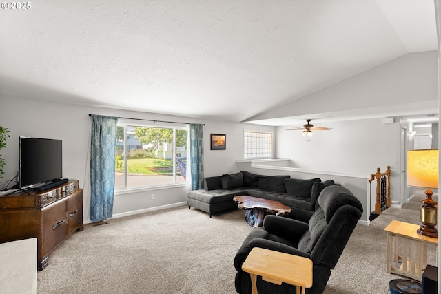 living area with vaulted ceiling, carpet, ceiling fan, baseboards, and a textured ceiling