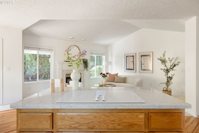 kitchen with white electric cooktop, light stone counters, a textured ceiling, open floor plan, and plenty of natural light