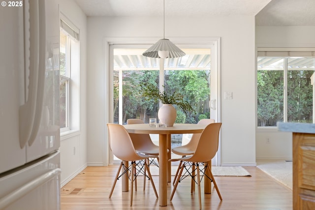 kitchen with white appliances, light wood finished floors, arched walkways, light countertops, and a breakfast bar