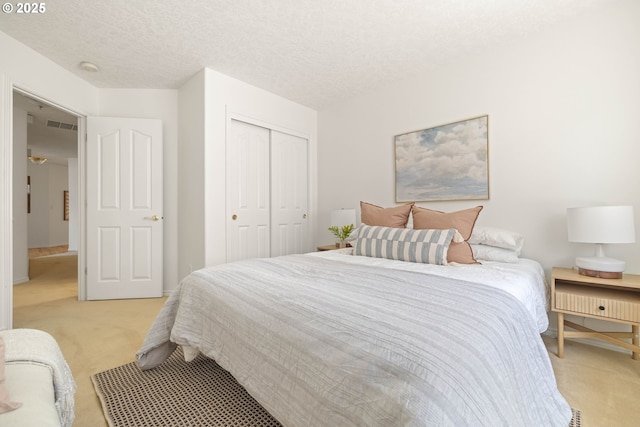 bedroom featuring light colored carpet, a closet, a textured ceiling, and baseboards