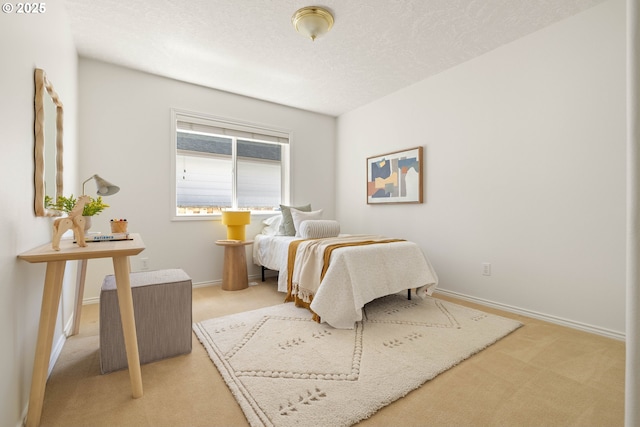 bedroom featuring light colored carpet, baseboards, and a textured ceiling