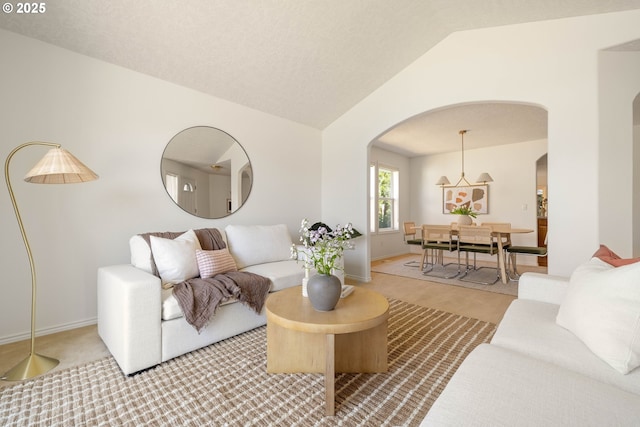 living room featuring arched walkways, lofted ceiling, and baseboards
