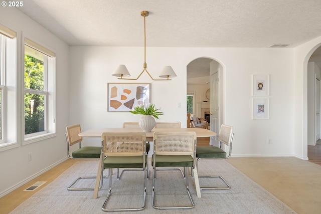 dining space featuring arched walkways, baseboards, and a textured ceiling