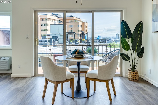 2021 SW Main St Unit 66, Portland, OR 97205 - dining room featuring wood finished floors, baseboards, a wall mounted AC, and a city view