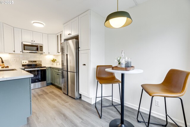 2021 SW Main St Unit 66, Portland, OR 97205 - kitchen featuring appliances with stainless steel finishes, a sink, light wood finished floors, tasteful backsplash, and light countertops