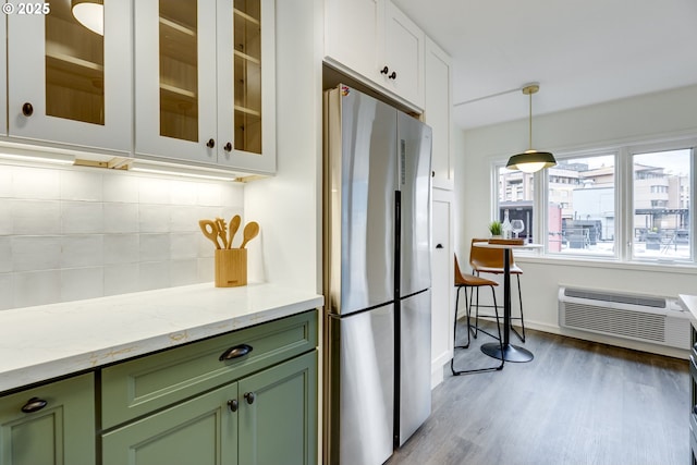 2021 SW Main St Unit 66, Portland, OR 97205 - kitchen with green cabinetry, freestanding refrigerator, tasteful backsplash, light wood-style flooring, and light stone counters