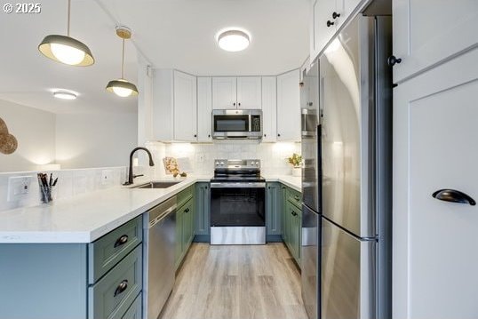 2021 SW Main St Unit 66, Portland, OR 97205 - kitchen with appliances with stainless steel finishes, backsplash, a sink, hanging light fixtures, and light wood-style floors