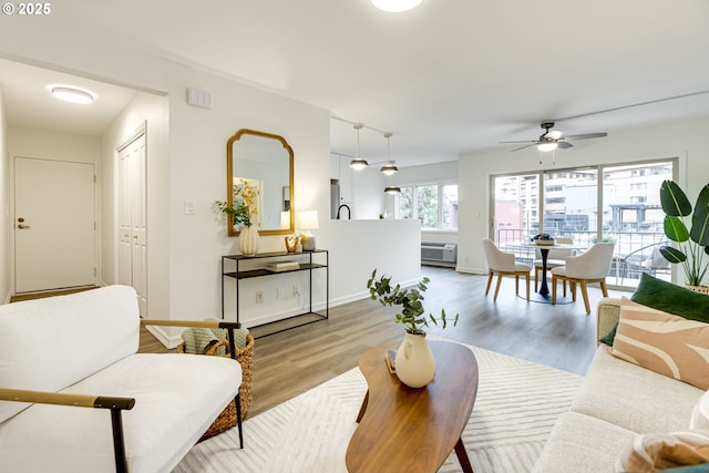 2021 SW Main St Unit 66, Portland, OR 97205 - living area featuring wood finished floors, a ceiling fan, a wall unit AC, and baseboards