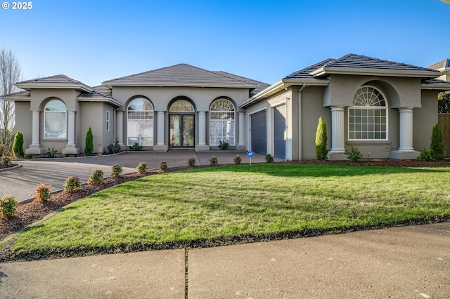 mediterranean / spanish-style home with a front lawn, a tiled roof, an attached garage, and stucco siding