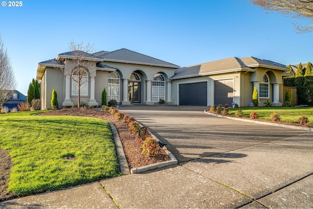 mediterranean / spanish house featuring driveway, a garage, a tiled roof, a front lawn, and stucco siding