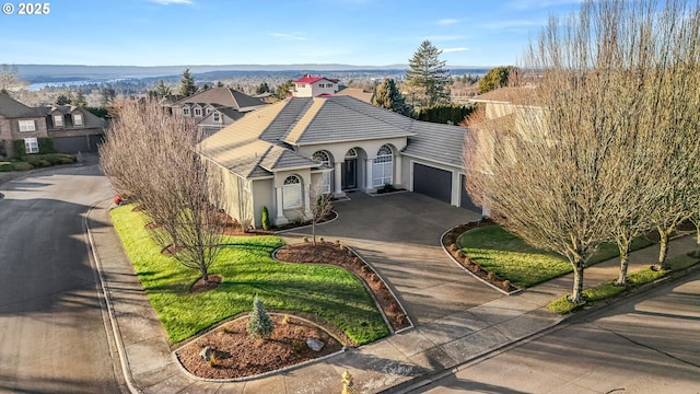 view of front of home with stucco siding, a garage, driveway, a tiled roof, and a front lawn